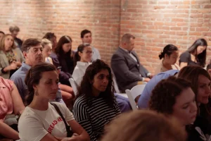 Close-up of attendees seated in white folding rental chairs during a seminar at a brick-walled NYC event space.