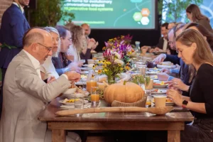 A fully set long communal table rental with floral decor and in-house A/V screens for a hybrid lunch-and-learn event in NYC.