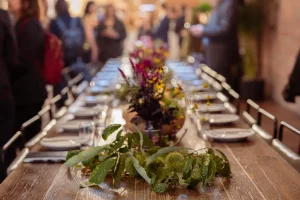 Long rustic wooden communal table with floral centerpieces and plateware rentals for a private dinner in NYC.
