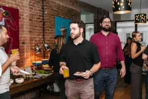 Industry professionals networking at a chic corporate social in a sun-lit Manhattan loft gallery.