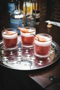 Close-up of signature red cocktails garnished with dried pear slices for a boutique brand activation.
