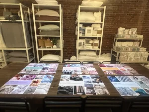 Stacked branded lookbooks and product catalogs on a wooden table for guests at a retail showcase.