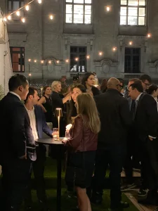 Professional guests networking during a corporate cocktail hour in a chic industrial loft in Midtown Manhattan.