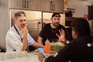 A private chef discussing the dinner menu with clients in the LOFT39 kitchen, showcasing the professional-grade appliances.