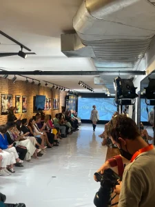 Wide view of a professional fashion runway setup with guest seating and stage lighting in a Manhattan gallery.