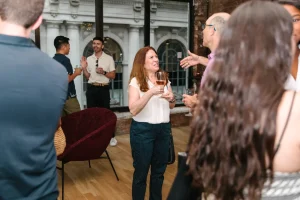 Diverse group of corporate executives networking at a private industry mixer in a Midtown loft gallery.