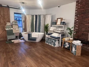 White retail shelving units against a historic exposed brick wall in a Manhattan warehouse gallery.
