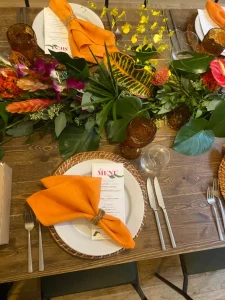 Bold tropical floral arrangements and orange linens for a themed private dinner.