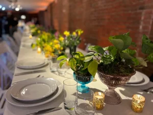 Wide shot of a dining loft featuring the signature brick wall and a long-table banquet setup.