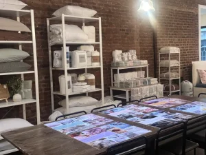 Custom white retail shelving unit displaying folded luxury bedding and home goods in a designer showroom.