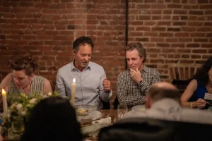 Guests engaged in lively conversation during a milestone birthday dinner celebration.