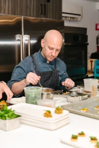 Focus shot of a chef's hands plating a refined course for a tasting menu.