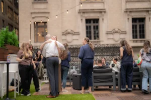 Friends celebrating a milestone event on the LOFT39 rooftop terrace, featuring cafe string lights and luxury outdoor flooring.
