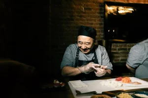 A professional sushi chef preparing fresh nigiri at a live-action station in the LOFT39 kitchen.