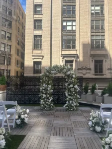 A night-view of a Manhattan rooftop wedding venue featuring warm bistro lights and architectural views.