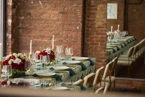 A couple in traditional South Asian wedding attire posing against an original red exposed brick wall in a Manhattan loft.