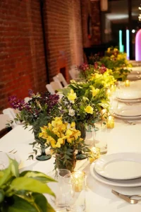 A simple and elegant floral arrangement in a gold vase sitting on a modern honeycomb-patterned wedding cocktail table.