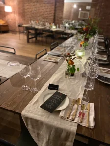 A professional bartender in a bowtie pouring a specialty cocktail during an NYC wedding welcome reception.