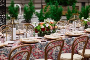 Elegant wedding dinner setup for a small guest count featuring gold chairs and designer floral linens.
