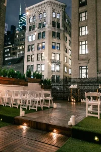 Overhead view of an outdoor wedding reception on a synthetic grass rooftop with a long feasting table.