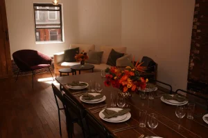 Wide shot of long farmhouse tables set with white plates and stainless steel flatware, creating a blank canvas for wedding decor.