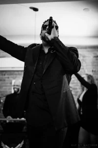 Dramatic black and white shot of a live musical performer singing under a spotlight at an upscale adult milestone birthday party.