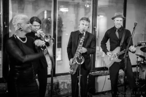 Sophisticated black and white capture of a live jazz singer hyping up a seated dinner crowd during a luxury 50th birthday bash.