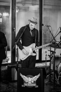 High-contrast monochromatic shot of a live guitarist playing an energetic set at an intimate milestone birthday lounge in NYC.