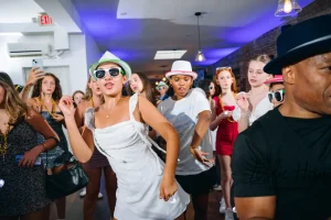 Energetic crowd of teens gathered around the DJ booth at a luxury industrial-chic loft party in New York City.