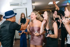 Dynamic party entertainer and MC leading group dances at a modern loft-style youth celebration in New York.