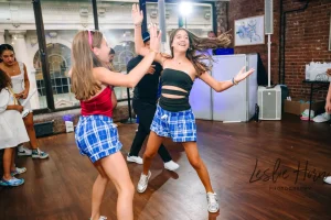 Guests lifting the guest of honor in a chair during the traditional Hora dance at a girls Bar Mitzvah party in a Manhattan loft.
