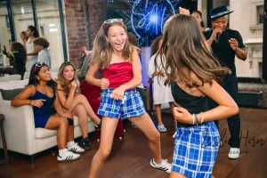 Large circle of family and friends holding hands and dancing the Hora at an upscale NYC Mitzvah celebration.