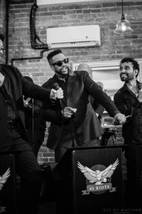 Candid black and white photo of a packed dance floor with guests laughing and celebrating a milestone birthday to a live DJ set.