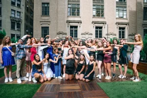 Kids gathered around an entertainment area during a high-energy teen dance party in a multi-story Manhattan venue.