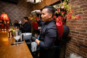 Candid photo of coworkers laughing and enjoying premium bar service in their winter holiday outfits.